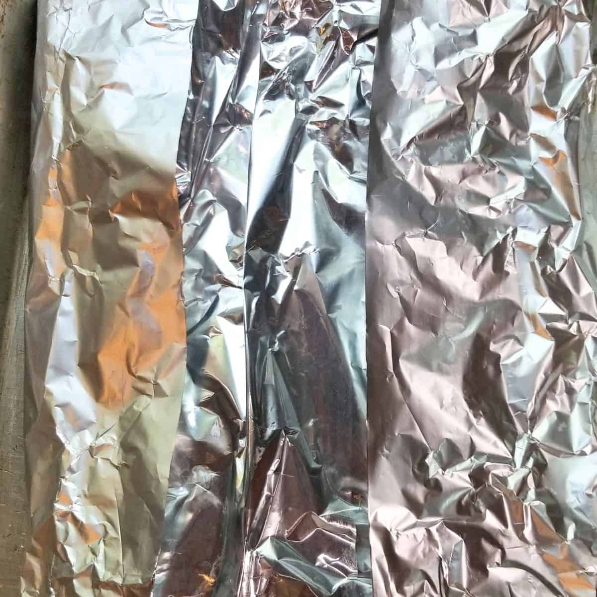 Pork spare ribs tightly covered with foil before baking low and slow in the oven.