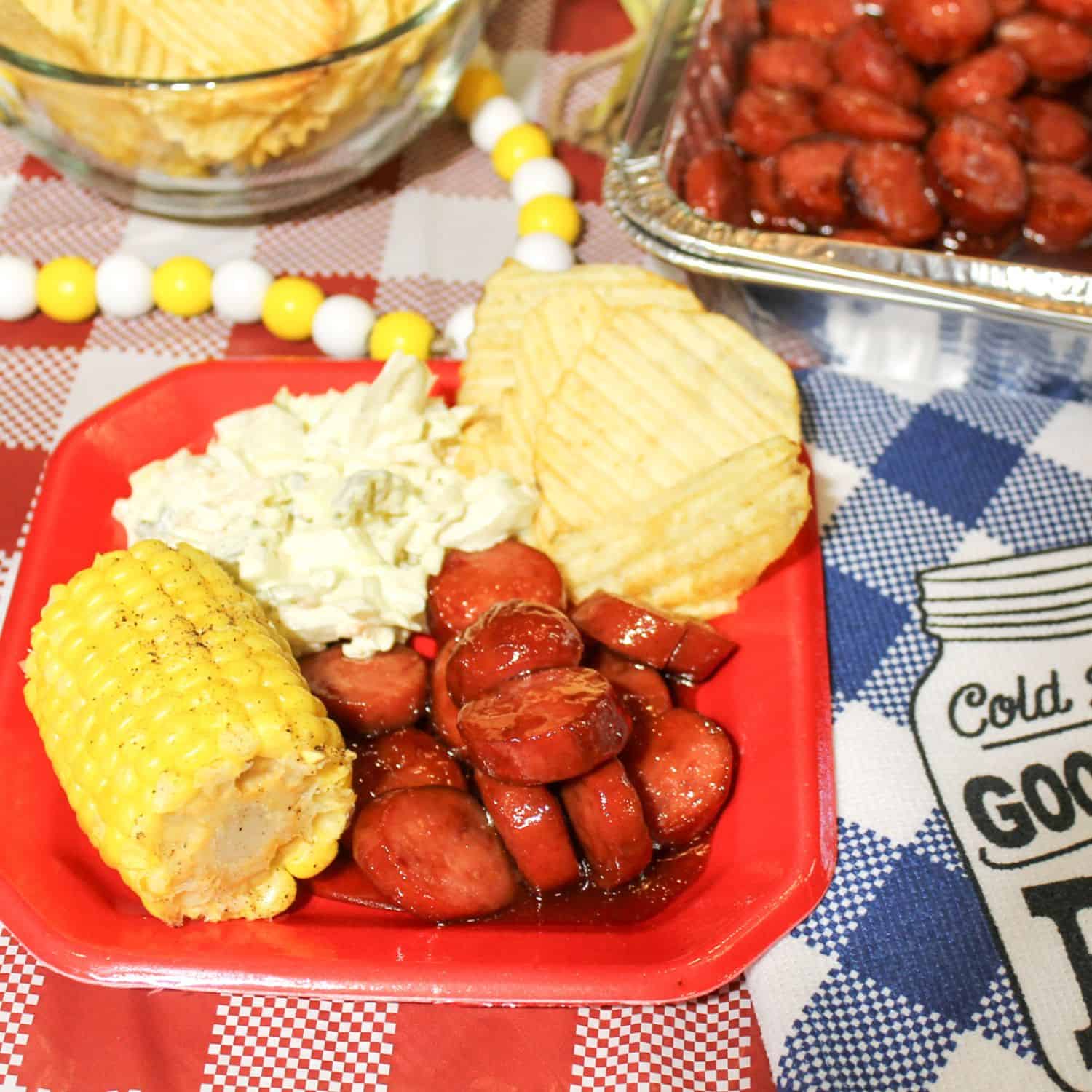Cooked barbecue sausage on a plate with other foods for a complete meal.