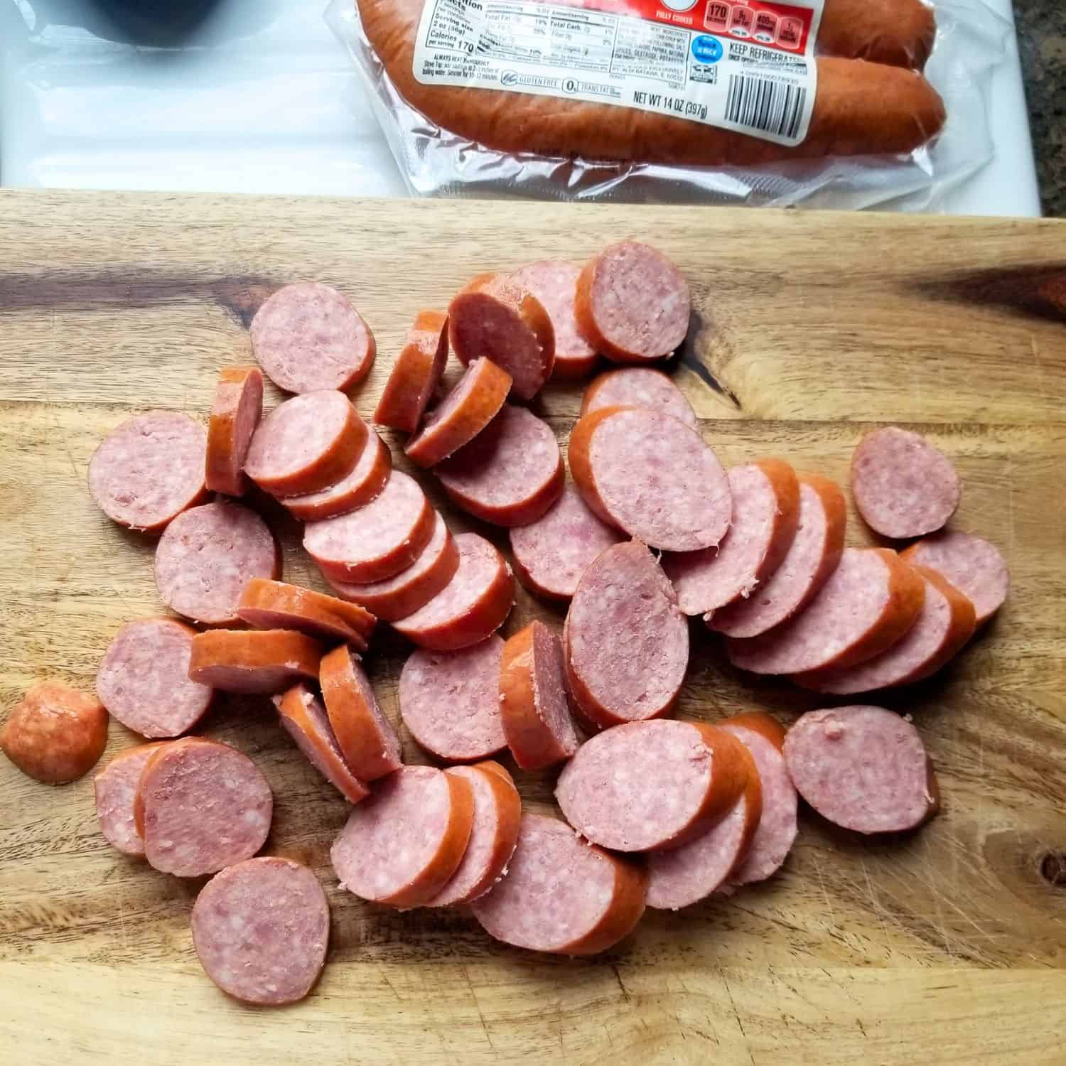 Cutting each smoked sausage into rounds on a cutting board.
