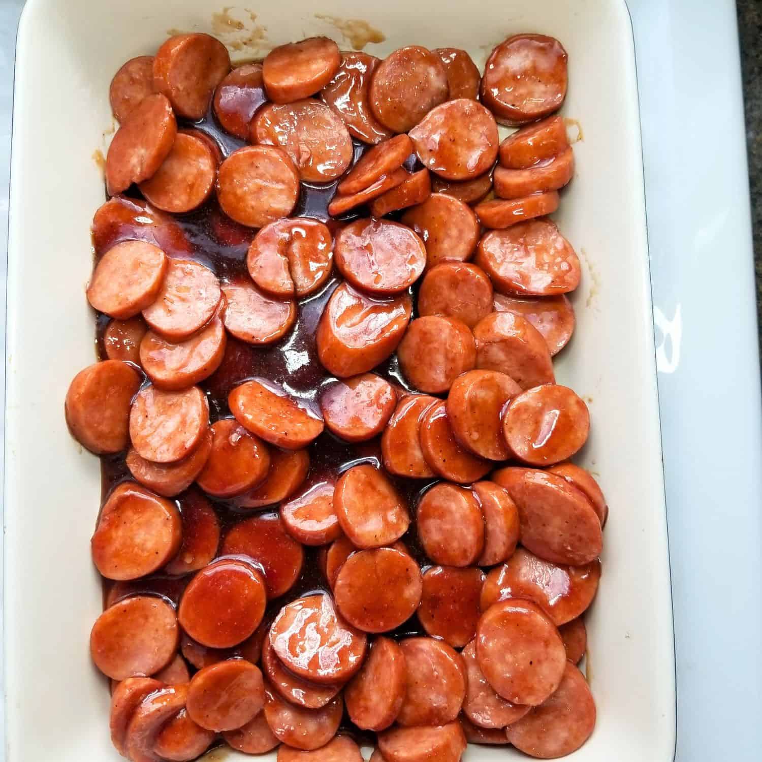 Adding BBQ sausage to a baking dish.