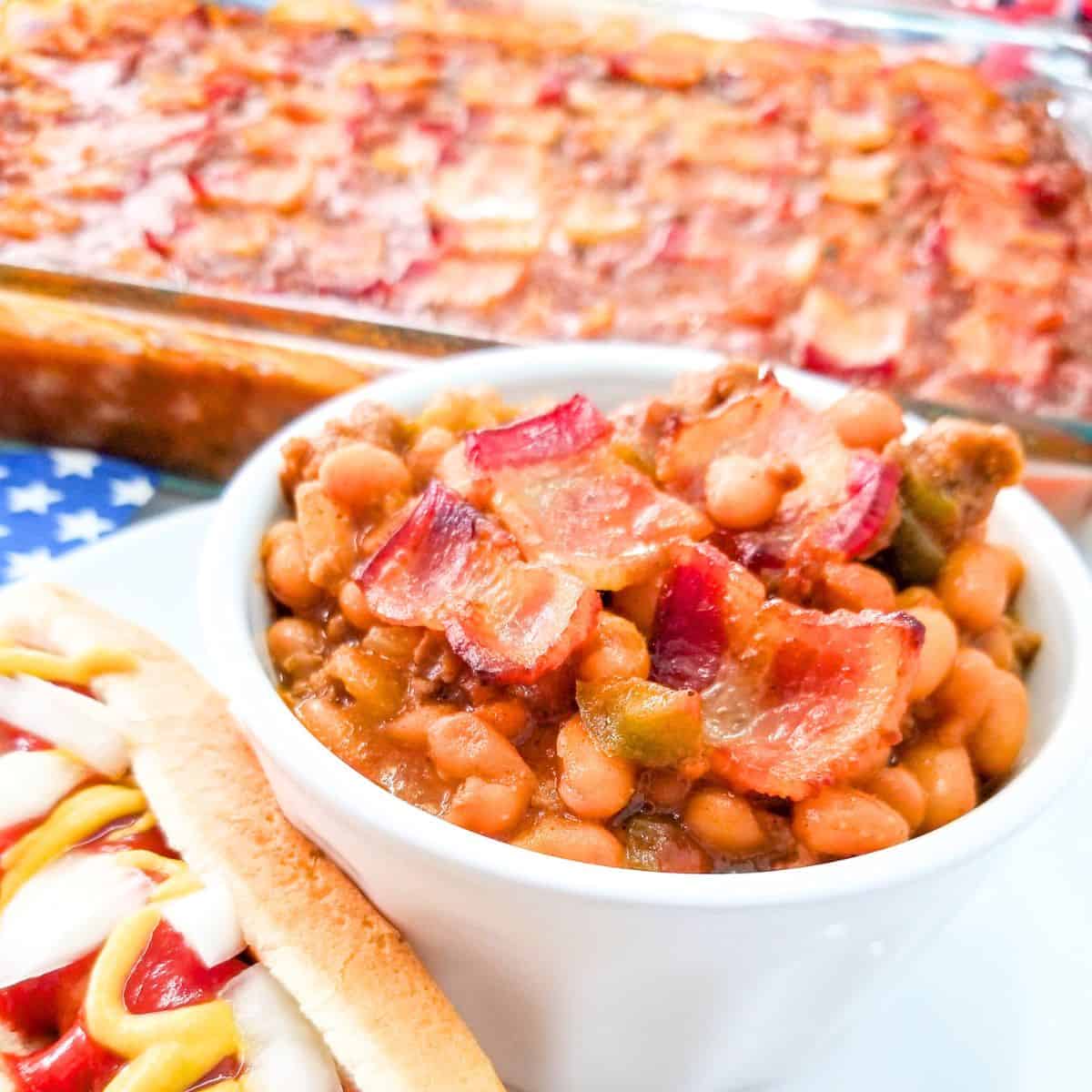 BBQ Baked Beans with Bacon served in a white baking dish with crispy bacon on top.