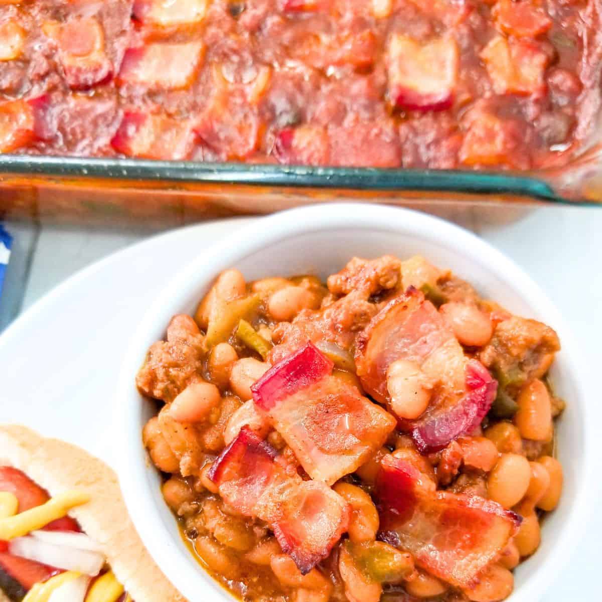 BBQ Baked Beans with Bacon served in a white baking dish with crispy bacon on top.