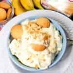 Banana pudding in a blue bowl with vanilla wafers, bananas and instant pudding.