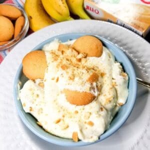 Banana pudding in a blue bowl with vanilla wafers, bananas and instant pudding.