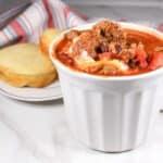 Beef and Sausage chili in a white bowl with cornbread on a white plate.