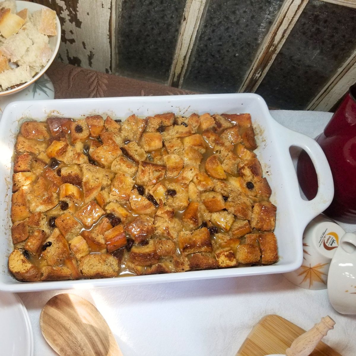 Freshly baked bread pudding with golden brown top in white baking dish.