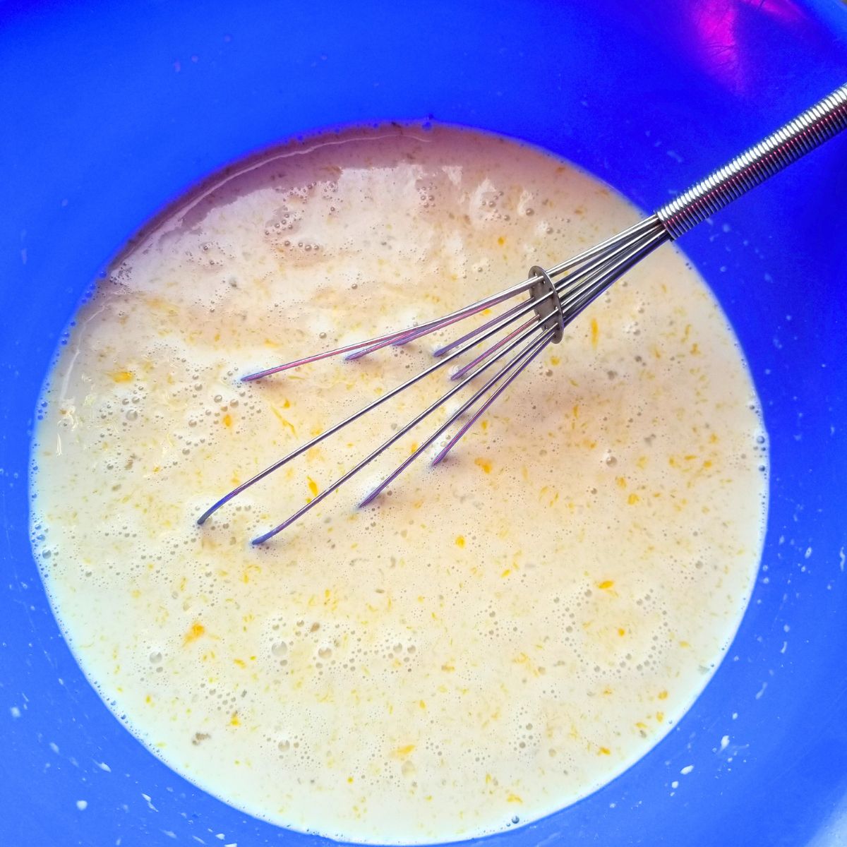 Whisked eggs, cream, and brown sugar in a mixing bowl.