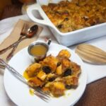 Freshly baked bread pudding with golden brown top in white baking dish and serving plate.