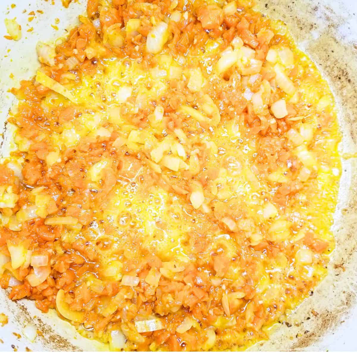 Carrots and onion cooking in a soup pot.