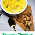 Broccoli Cheese Soup in a white bowl with a gold spoon and croutons.