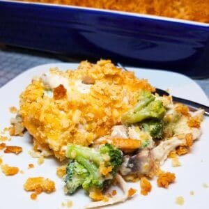 Creamy chicken casserole with broccoli and mushrooms topped with buttery Ritz crackers on a serving plate and in a baking dish.