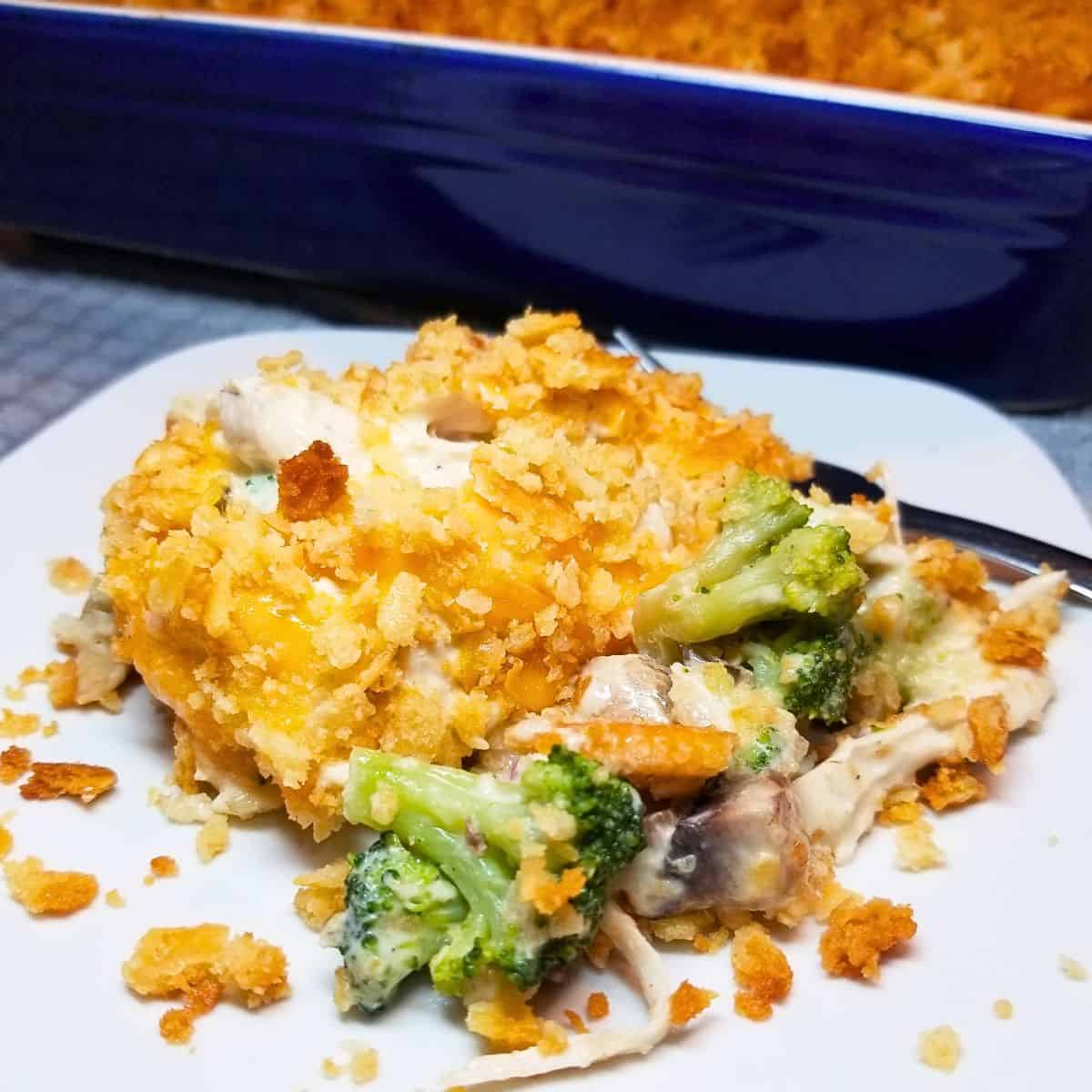 Creamy chicken casserole with broccoli and mushrooms topped with buttery Ritz crackers on a serving plate and in a baking dish.