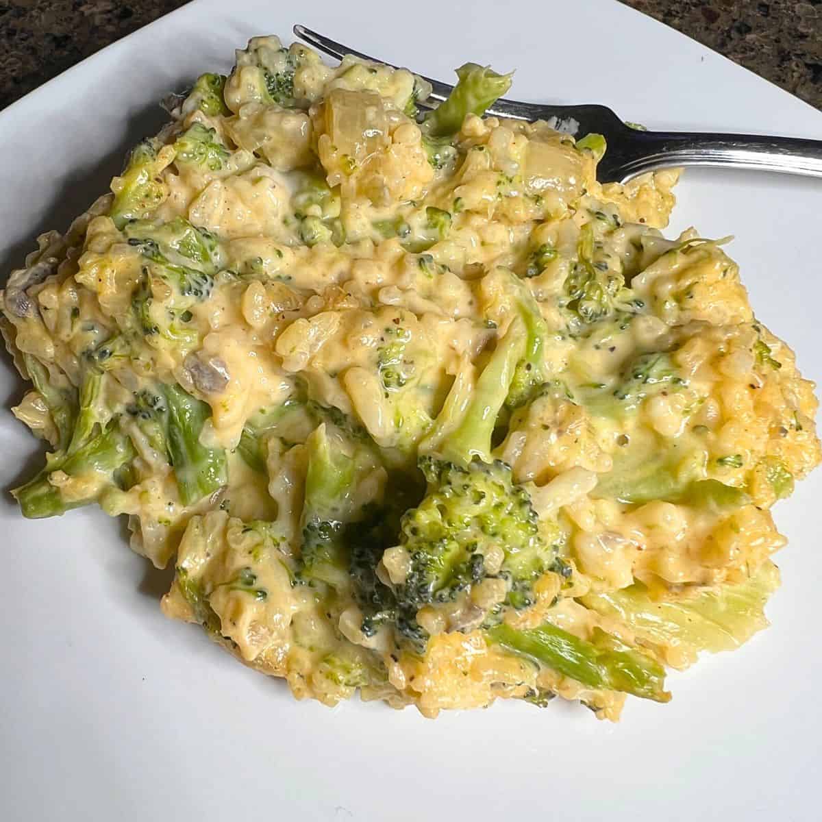 Cheesy Broccoli Rice Casserole on a white plate with a fork.