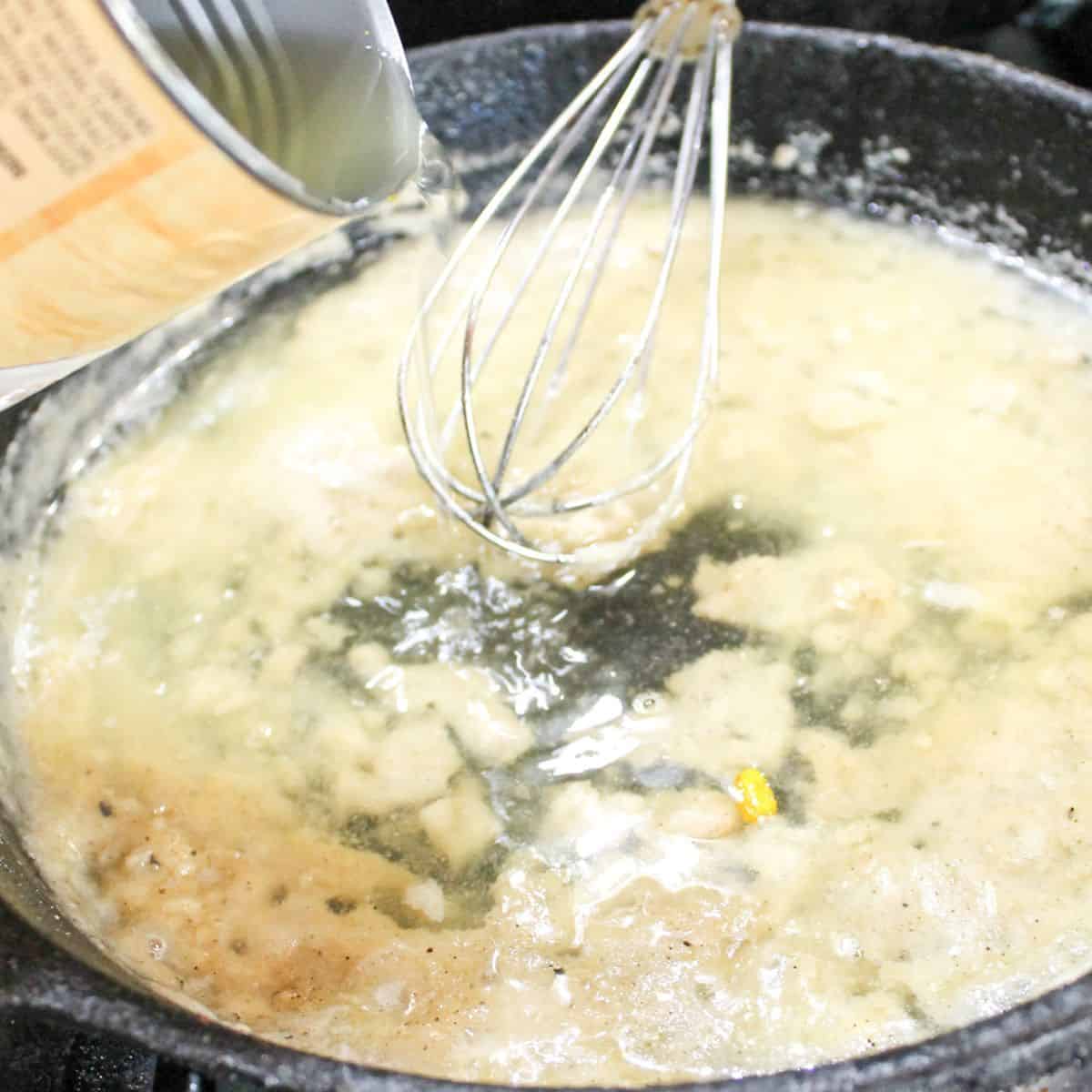 Adding beef broth to the mixture in the cast iron skillet.