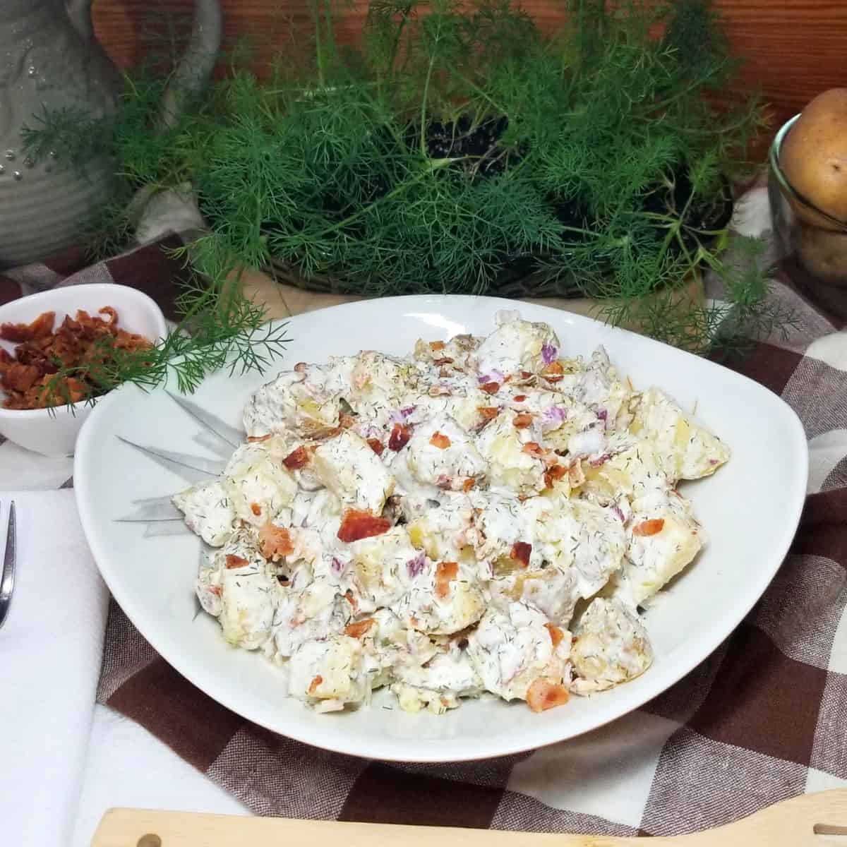 Potato salad in a bowl sitting on a farmhouse table.