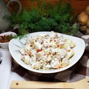 Cold potato salad in a bowl sitting on a farmhouse table.