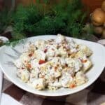 Cold potato salad in a bowl sitting on a farmhouse table.