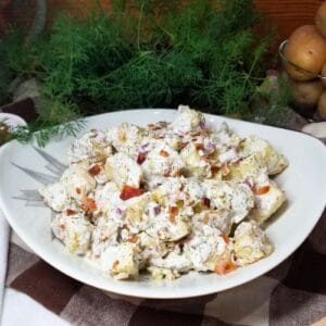 Cold potato salad in a bowl sitting on a farmhouse table.