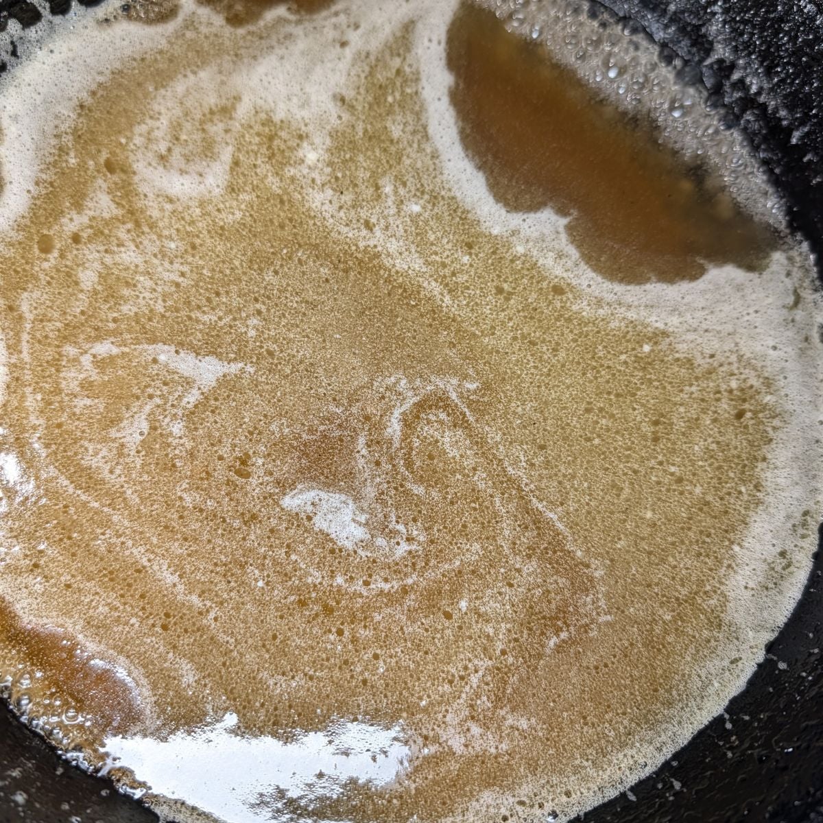 Butter and syrup melting in a cast iron skillet.