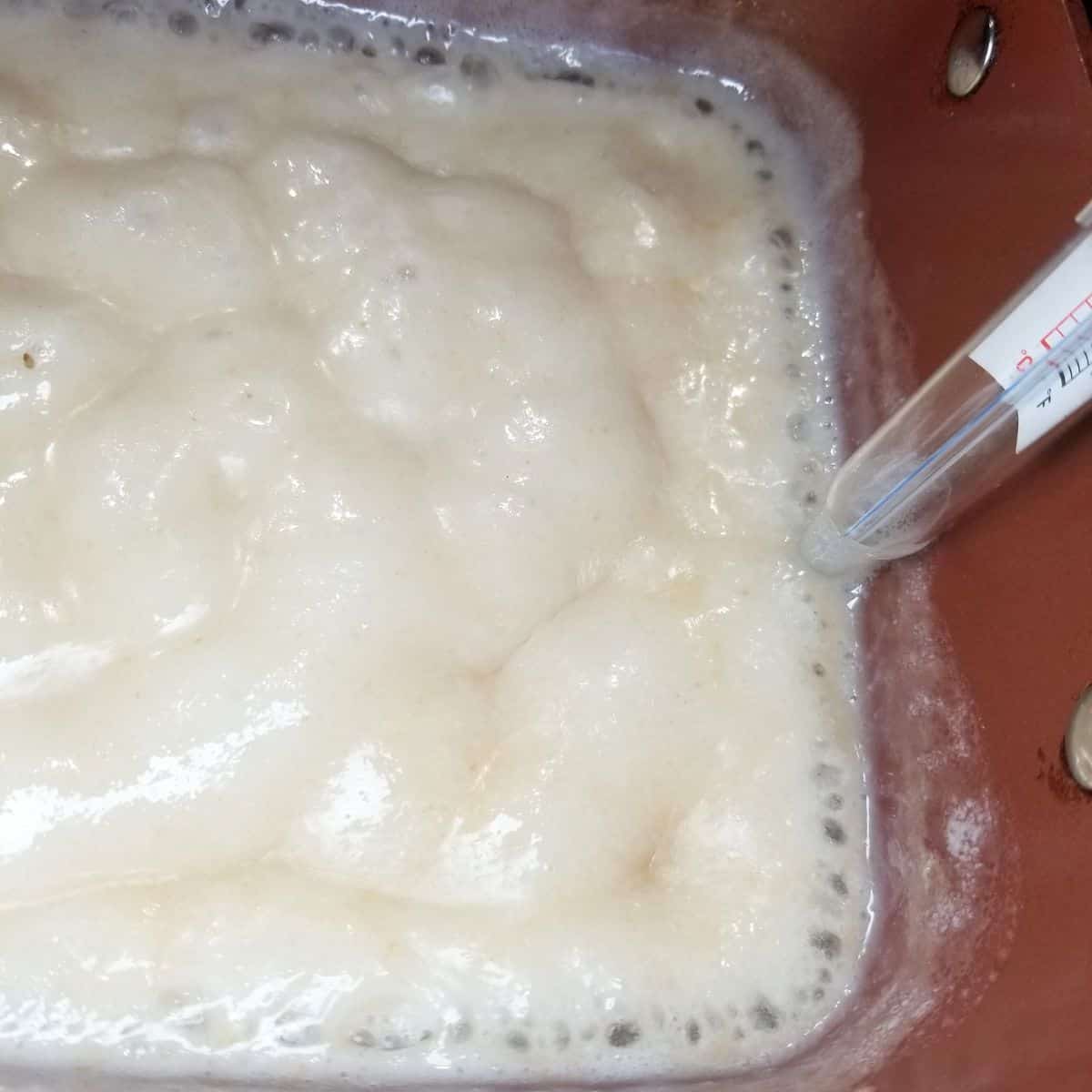 Boiling ingredients in a saucepan with a candy thermometer.