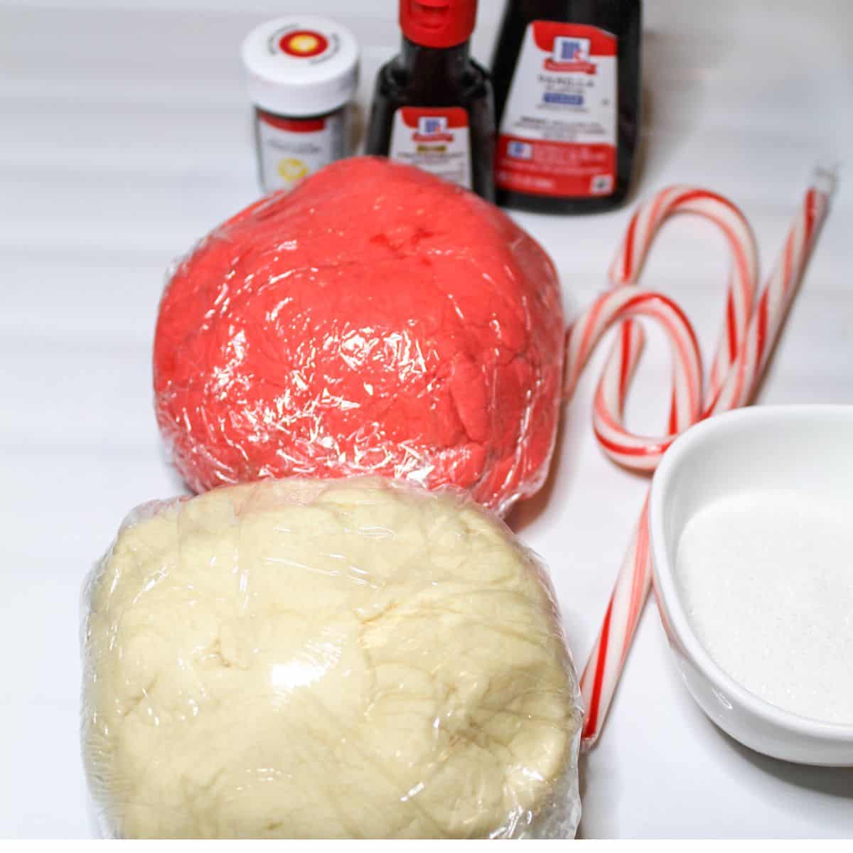Red and white dough wrapped in plastic wrap, candy canes, and flavoring.