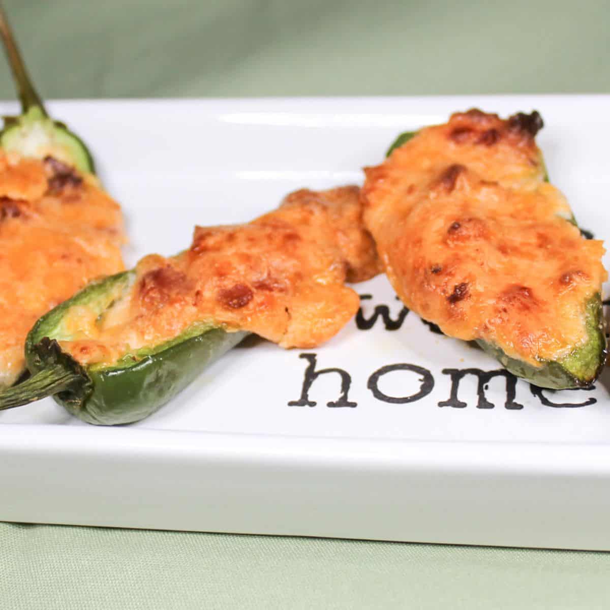 Baked jalapeno peppers on a white serving dish.