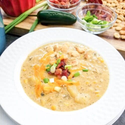 Chicken chowder in a white bowl with ingredients shown behind the bowl.