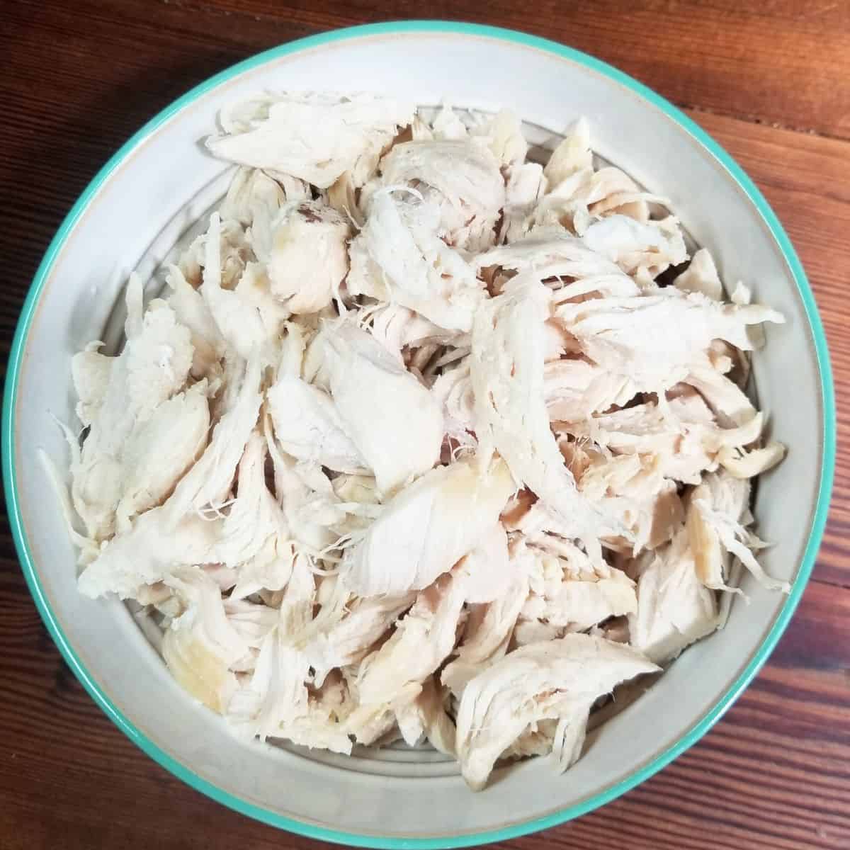 Cooked chicken tenders chopped into bite size pieces in a bowl.
