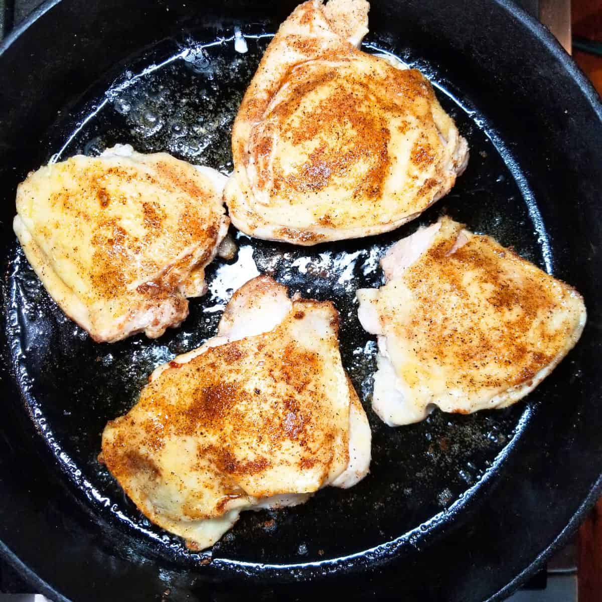 Browning chicken in a skillet on the stovetop.