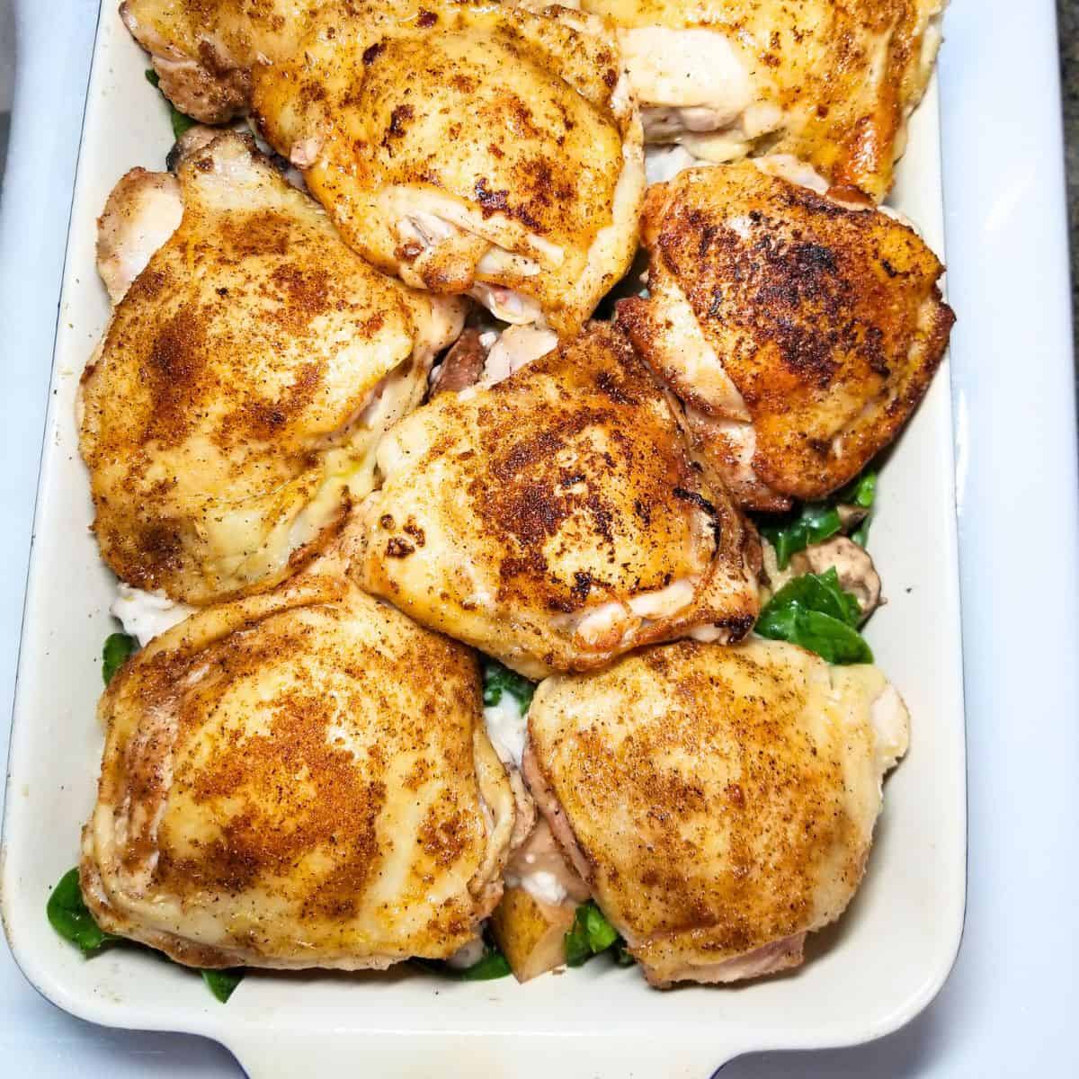 Chicken added to the top of the vegetables in a baking dish.
