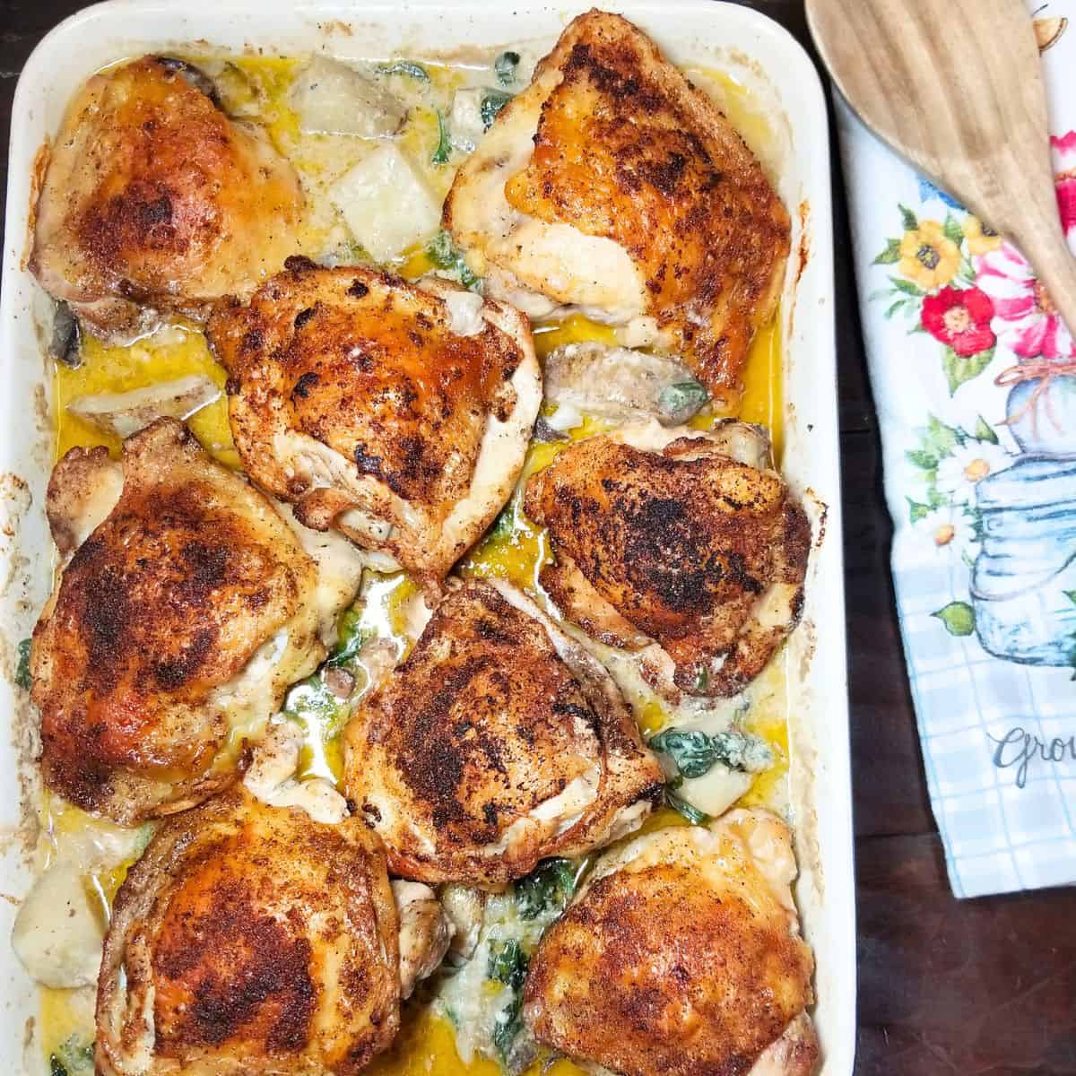 Cooked oven baked chicken and potatoes in a baking dish ready to serve.
