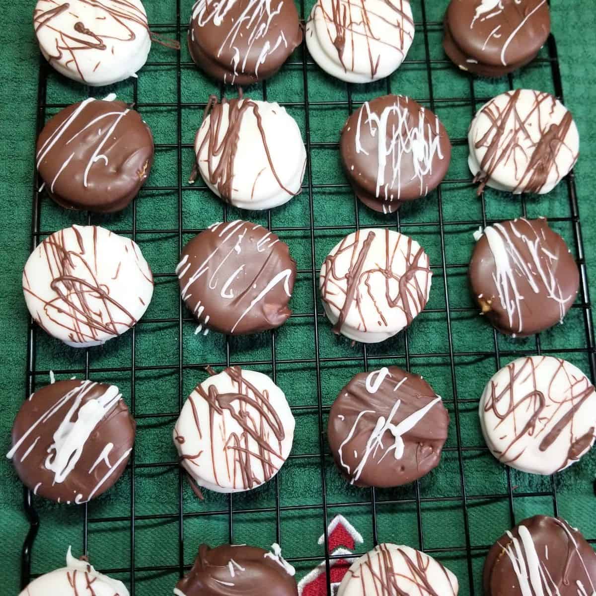 Ritz cracker cookies on a baking rack with a green towel under the rack.