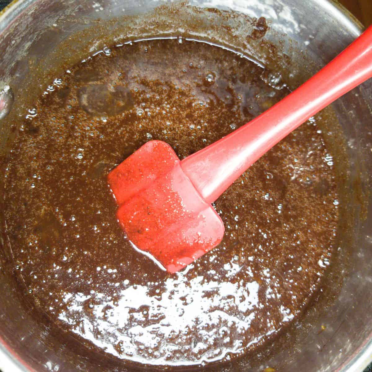 Melted chocolate in a pan with a red spatula.