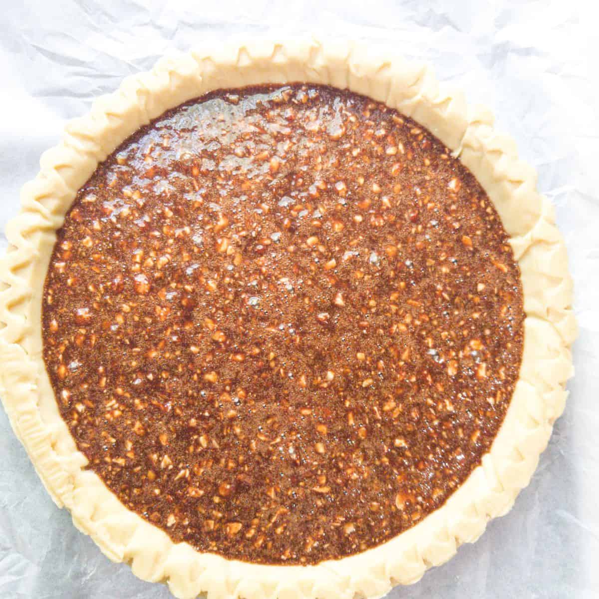 Pecan pie filling in a pie crust ready to bake.
