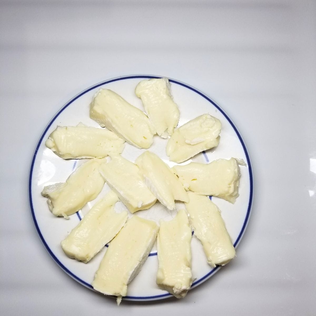 Sliced brie cheese on a white plate.