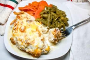 Chicken on a white plate with green beans and carrots.