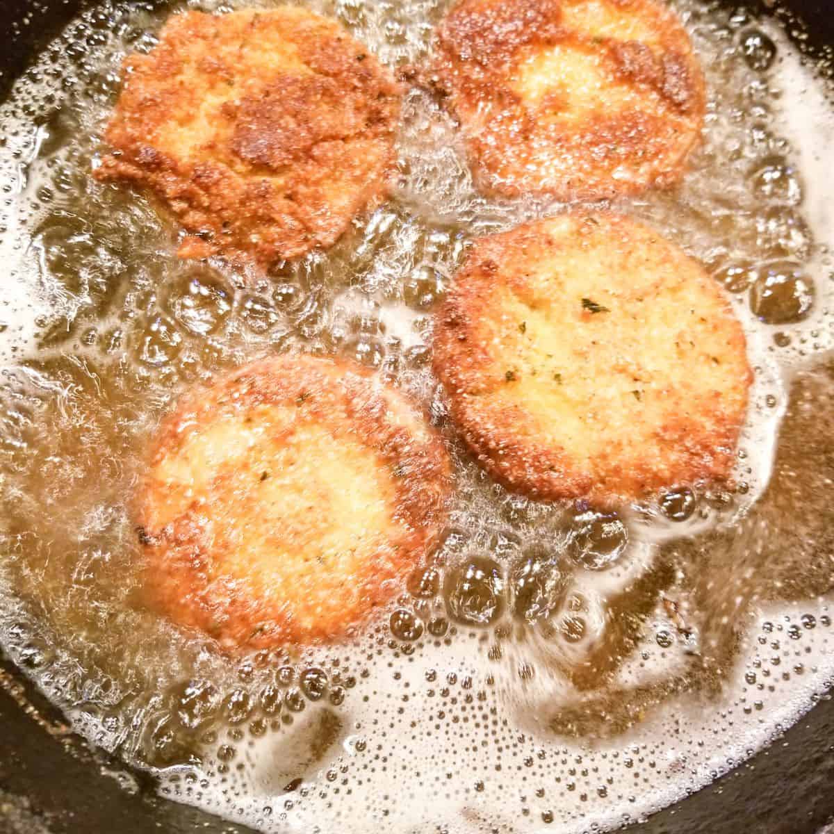 Frying tomatoes in oil in a cast iron skillet.