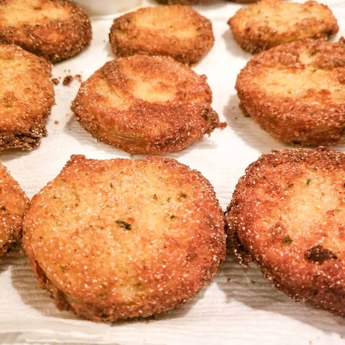 Breaded and fried tomatoes on a paper towel lined plate.