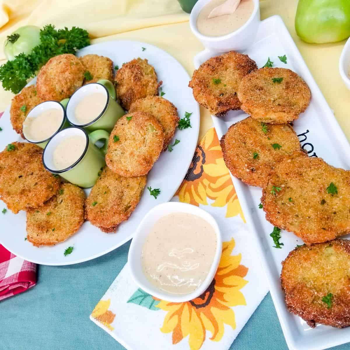 Two white dishes with fried tomatoes and one white dish with dipping sauce, a sunflower towel and a red and white napkin.
