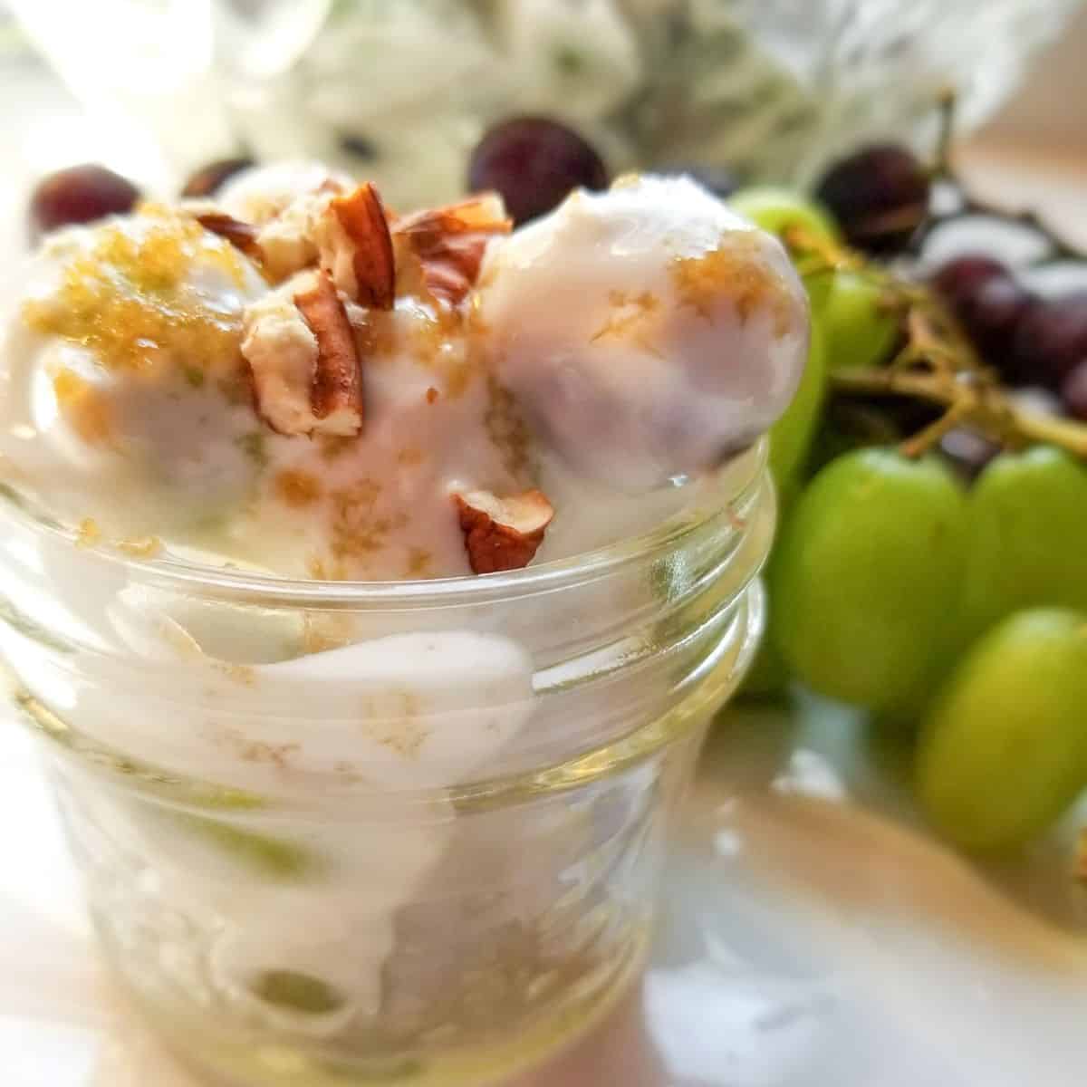 Grape salad in a serving dish with green grapes on the table.