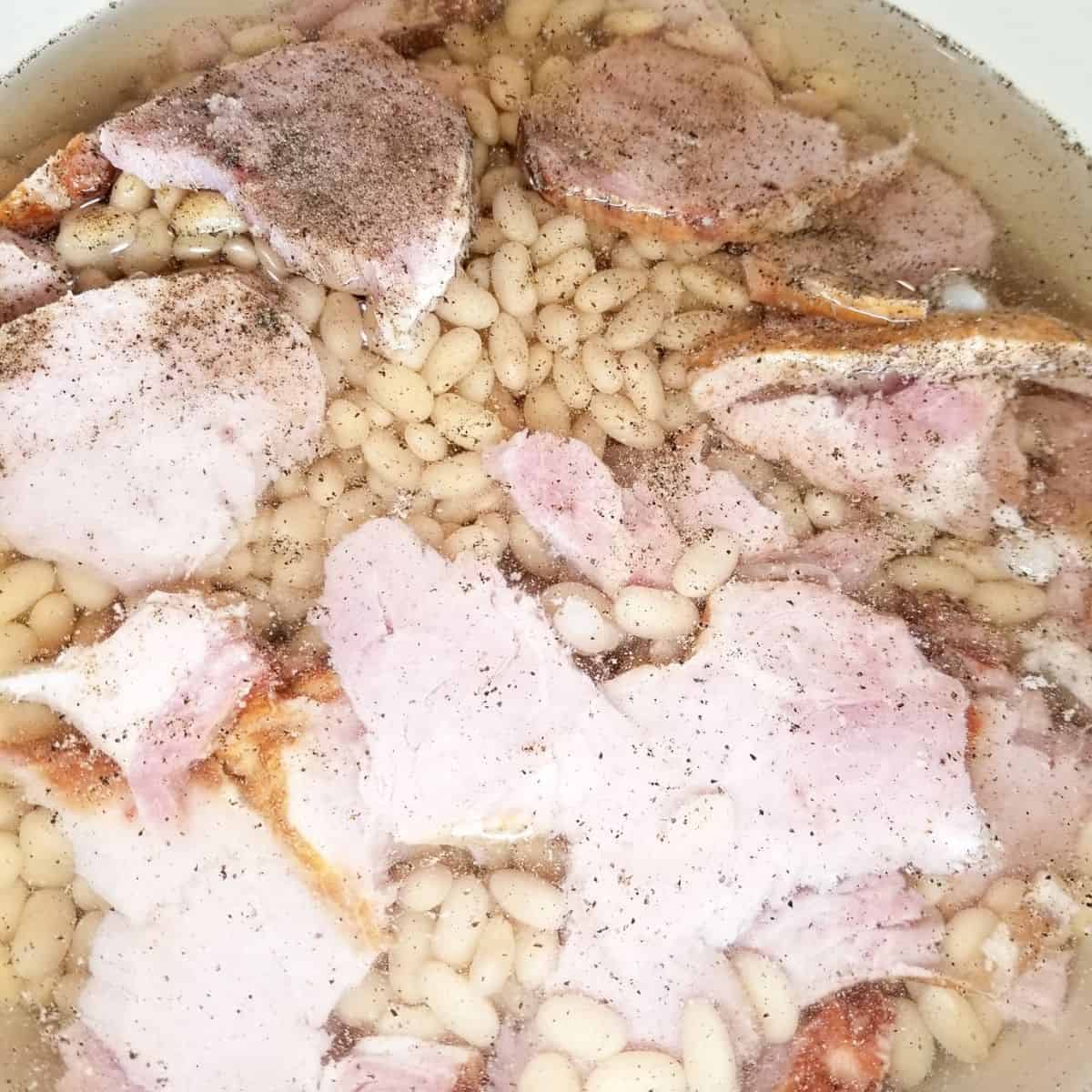Adding the remaining ingredients to the beans in the pot.