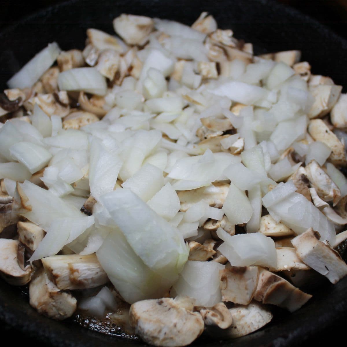 Onions and mushrooms in a skillet.