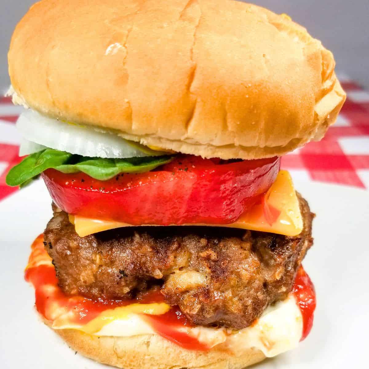 A grilled hamburger ready to eat and loaded with toppings.