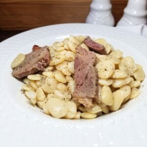 Ham and Beans in a white bowl on a table.