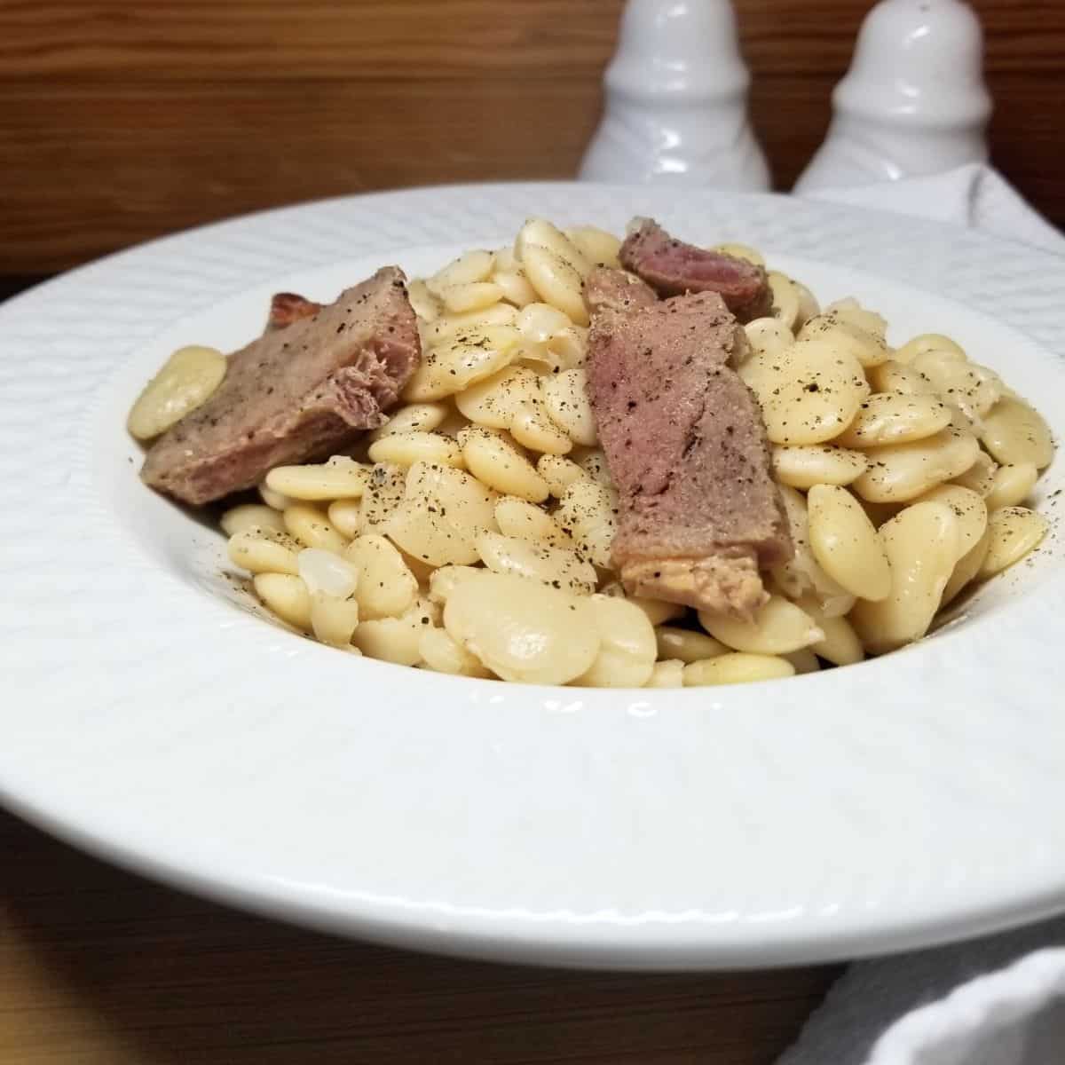 Close-up of tender lima beans and smoked ham in rich homemade broth.