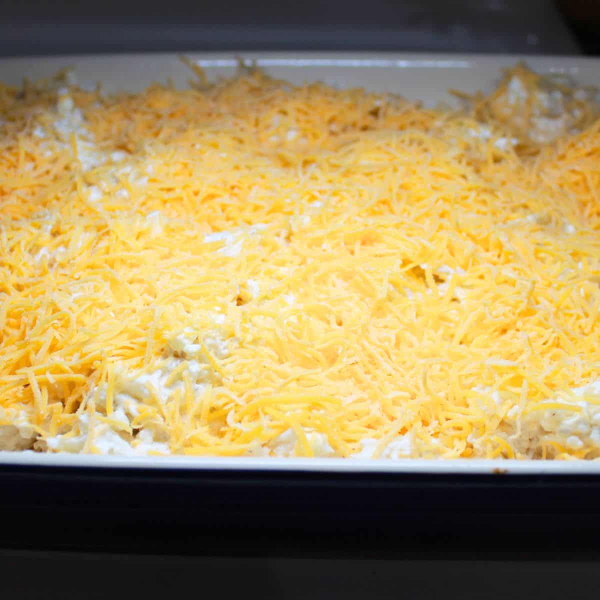 Adding cheese to the top of the casserole.