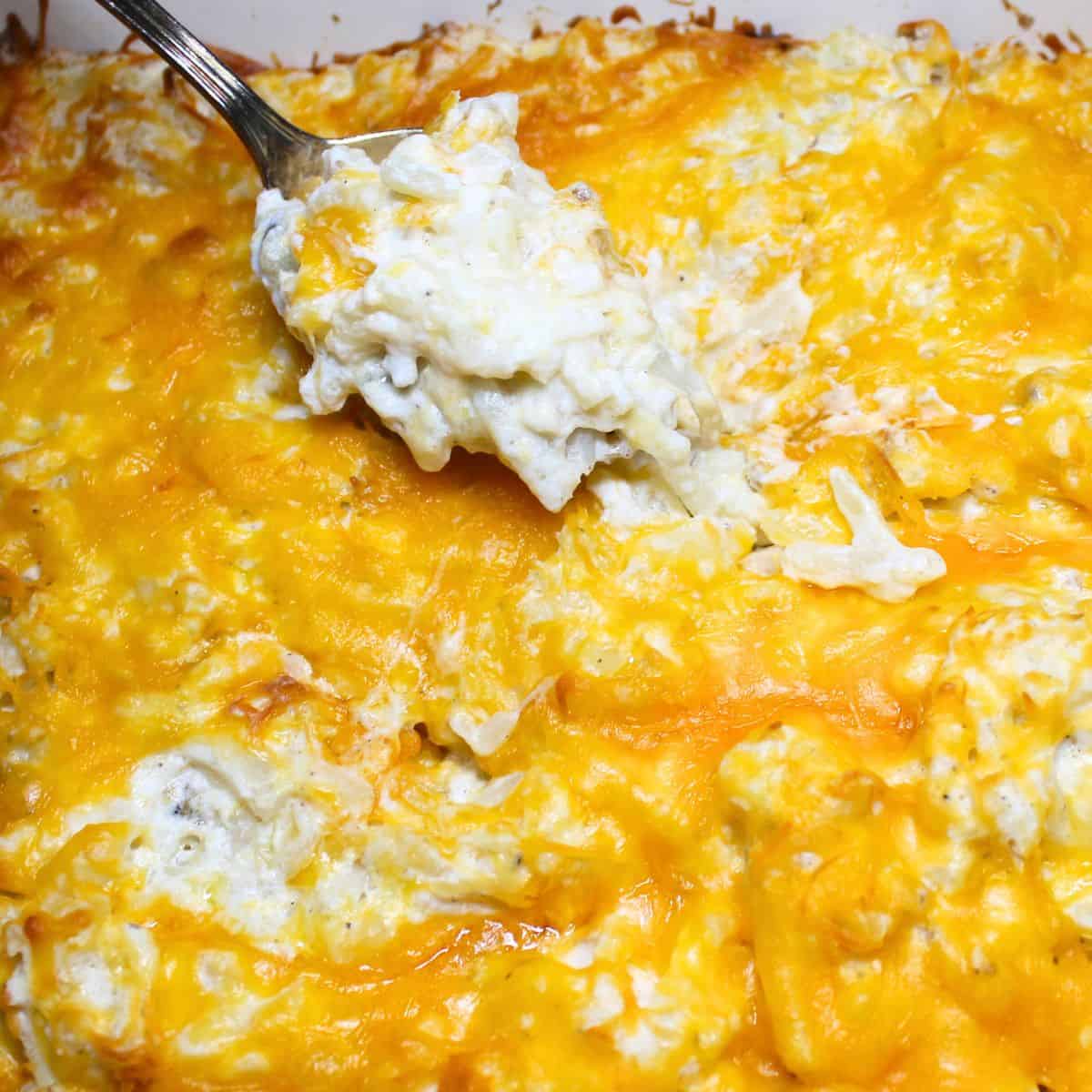 The cooked hash brown casserole in a baking dish with a spoon.