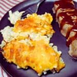 Hash Brown casserole on a black plate with a fork and bbq.