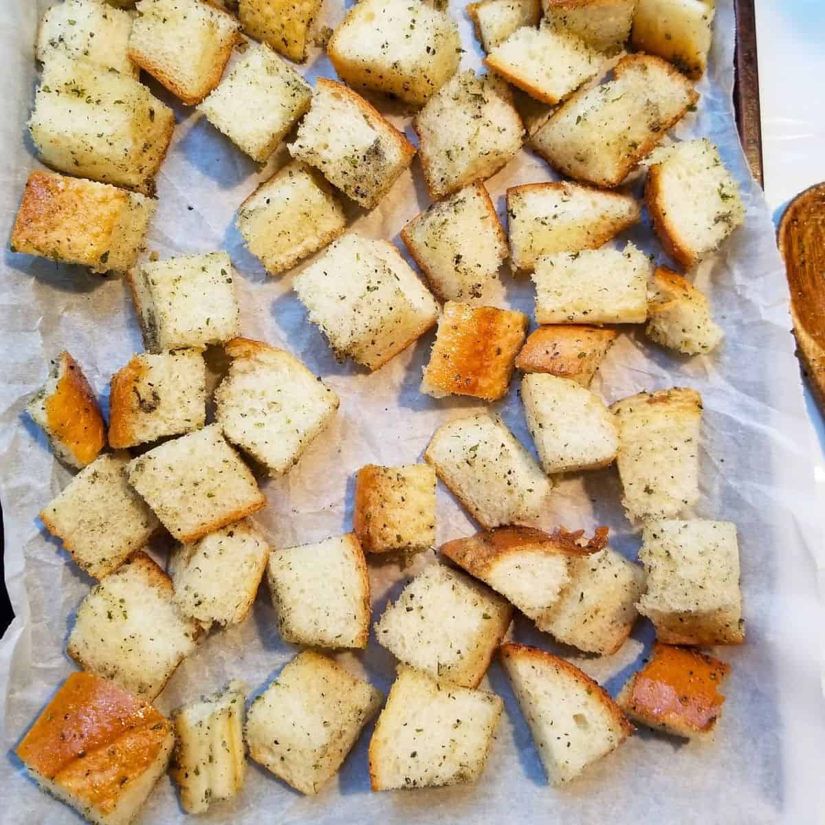 A baking sheet lined with parchment paper and covered with bread cubes.