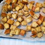Baked croutons on a parchment paper lined baking sheet.